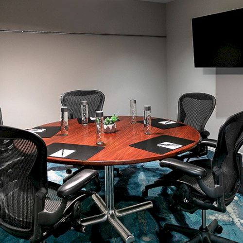 Modern conference room with a wooden boardroom table, swivel chairs, and drinks.