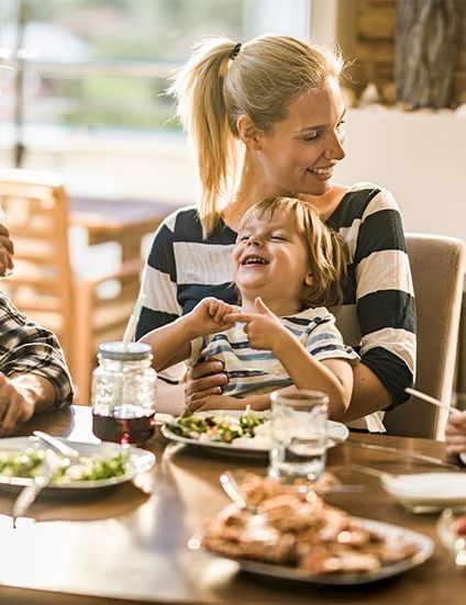 A family at a dining table sharing a cozy, laughing meal in a bright home.
