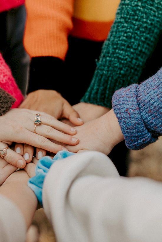 Hands and rings in a circle, as people in cozy sweaters hold and touch each other in a warm, loving gesture.